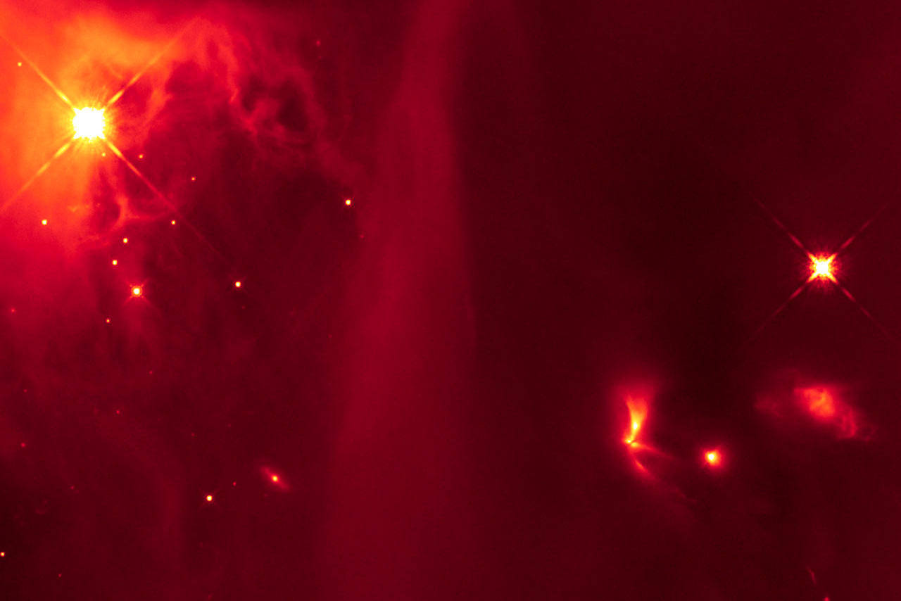 This infrared image from the Hubble Space Telescope contains a bright, fan-shaped object (lower right quadrant) thought to be a binary star that emits light pulses as the two stars interact. The primitive binary system is located in the IC 348 region of the Perseus molecular cloud and was included in the study by the Berkeley/Harvard team.