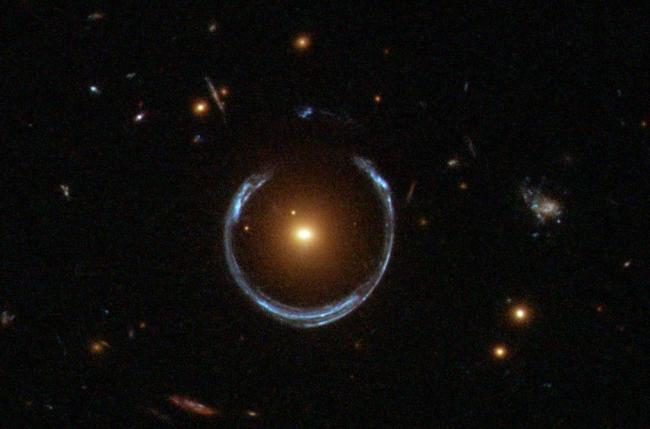 Hubble image of a red galaxy acting as a gravitational lens for a more distant blue galaxy