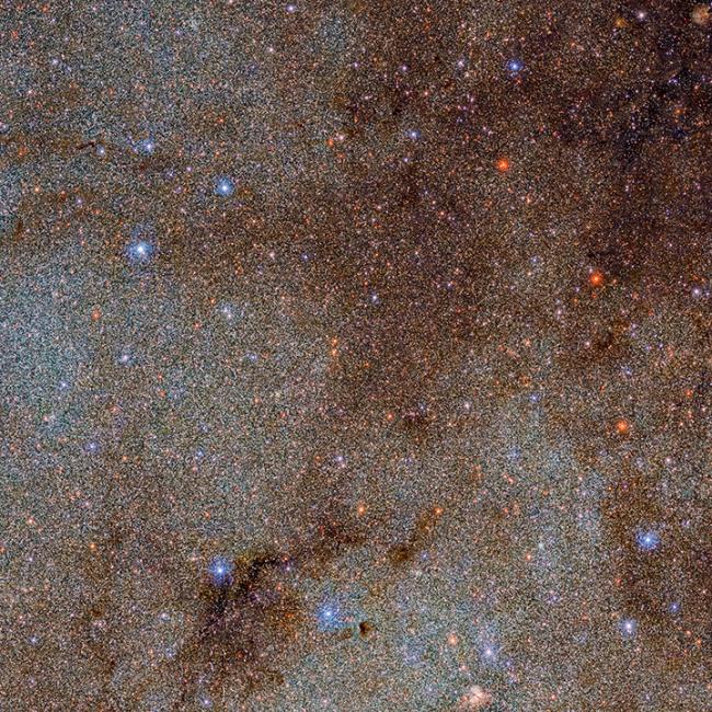 This image, which is brimming with stars and dark dust clouds, is a small extract — a mere pinprick — of the full Dark Energy Camera Plane Survey (DECaPS2) of the Milky Way.