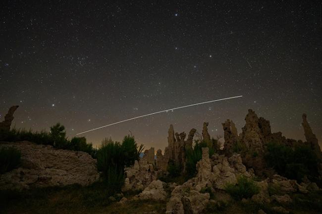 The International Space Station traces its path across the twilight sky over a California desert landscape.